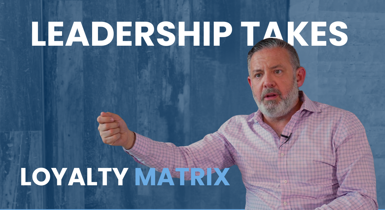 Phil Shawe in a pink shirt gesturing in front of a wood paneled wall